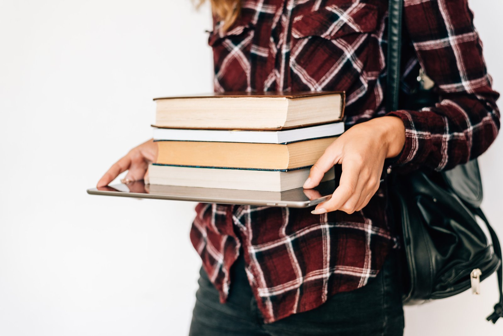 hands of a girl holding a tablet and a stack of books. the concept of knowledge. copy space